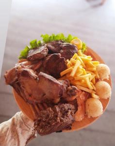 a person holding a plate of food with meat and fries at Villa Mulliri in Peje