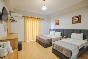 a hotel room with two beds and a flat screen tv at Hotel Milo Ksamil in Ksamil