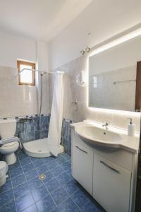 W łazience znajduje się umywalka, toaleta i lustro. w obiekcie Hotel Milo Ksamil w mieście Ksamil