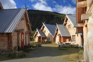una fila de edificios de madera con montañas en el fondo en Viking Cabins - MIT FabLab - Solvik, en Kvalvik