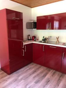 uma cozinha com armários vermelhos e piso em madeira em Hôtel la Kinkerne em Morzine