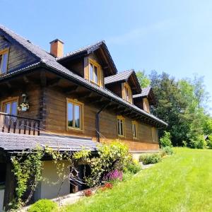 a wooden house with a green lawn in front of it at ORLIK - pokoje gościnne in Uście Gorlickie