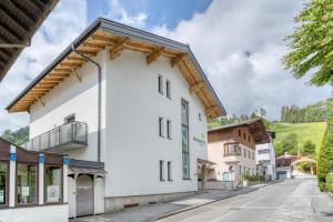 a white building with a wooden roof on a street at Apartment Annemarie in Zell am See