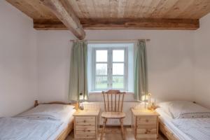 2 Betten in einem Zimmer mit einem Stuhl und einem Fenster in der Unterkunft Eider Domizil No1 in Oldenswort