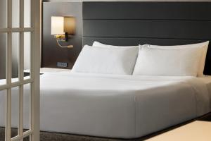 a bed with white sheets and pillows in a room at Crowne Plaza Knoxville Downtown University, an IHG Hotel in Knoxville