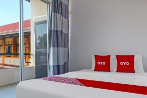 ein weißes Bett mit roten Kissen in einem Zimmer in der Unterkunft OYO 92593 Penginapan Sultan Haji 1 in Bandar Lampung