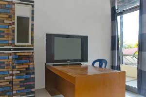 einen TV auf einem hölzernen Schreibtisch in der Unterkunft OYO 92593 Penginapan Sultan Haji 1 in Bandar Lampung