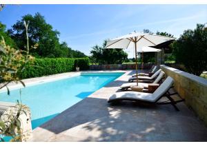 a swimming pool with lounge chairs and an umbrella at Domaine de Plisseau in Le Rigalet