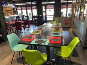 un lungo tavolo in un ristorante con sedie verdi di Le Relais De La Place a Le Faou