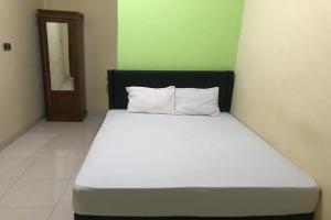 OYO 92608 Penginapan Mc Lodge في لابوان باجو: سرير بشرشف ووسائد بيضاء في الغرفة