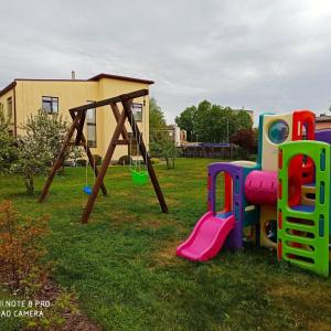 un parque infantil con columpios en el césped en Cozy Apartment Magnolia 3 Room, en Ventspils
