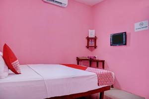 a pink bedroom with a bed and a tv at OYO 92598 Sulthan Homestay Syariah 3 in Palembang