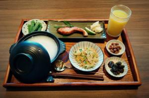 a tray with a plate of food and a glass of orange juice at Jiaoxi Pusu Homestay in Jiaoxi