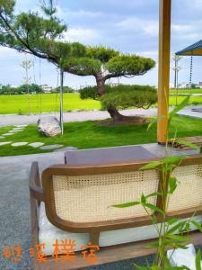 eine Bank auf einer Veranda mit einem Baum in der Unterkunft Jiaoxi Pusu Homestay in Jiaoxi