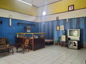 um quarto com paredes azuis e uma televisão e cadeiras em SPOT ON 92601 Penginapan Keluarga em Medan