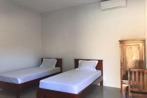 dwa łóżka w pokoju z białą pościelą w obiekcie OYO 92603 Lidya Homestay w Labuan Bajo