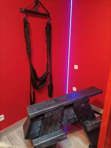 eine Holzbank in einem Zimmer mit einer roten Wand in der Unterkunft Appartement Le Secret Spa billard sensualité in Espondeilhan