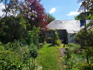 um jardim em frente a uma casa com flores em BARHOLM CROFT Holiday Cottage em Creetown