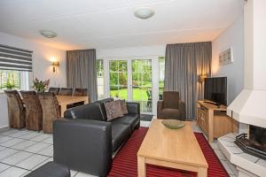 a living room with a couch and a television and a table at Vakantiepark Hellendoorn in Hellendoorn