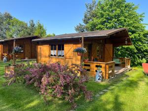 a small wooden house with flowers in front of it at Domki Radków - Skibin in Radków