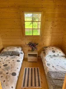 two beds in a log cabin with a window at Domki Radków in Wünschelburg