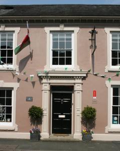 a pink building with a black door and a flag at The New White Lion in Llandovery