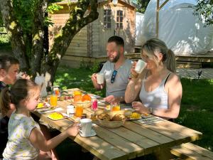 Eine Gruppe von Menschen, die an einem Picknicktisch sitzen und Essen essen. in der Unterkunft Au Domaine du Prédieu in Crécy-sur-Serre