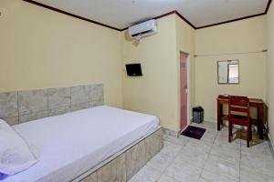 een slaapkamer met een bed, een stoel en een bureau bij OYO 92619 Inn Homestay in Lombok