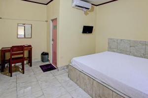 een slaapkamer met een bed, een bureau en een stoel bij OYO 92619 Inn Homestay in Lombok