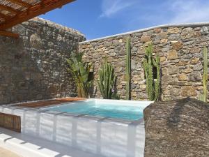 a swimming pool in front of a stone wall at Teal Rock Mykonos in Ano Mera