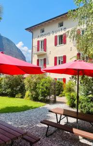 zwei Picknicktische und Sonnenschirme vor einem Gebäude in der Unterkunft Albola Suite Holiday Apartments in Riva del Garda