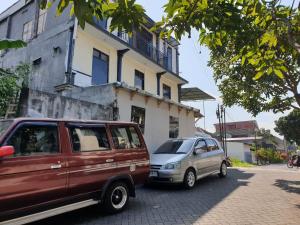 dwa samochody zaparkowane na ulicy przed budynkiem w obiekcie OYO Life 92622 Jatiluhur Kost Syariah w mieście Malang