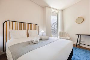 sypialnia z dużym białym łóżkiem i oknem w obiekcie Upscale Apartment in City Center by LovelyStay w Lizbonie