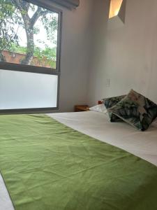 a bedroom with a green blanket on a bed with a window at Hotel Parador del Gitano in Doradal