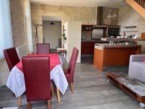 cocina y comedor con mesa roja y sillas en Le Loft Ancien Haras de la Tour en Lamothe-Landerron