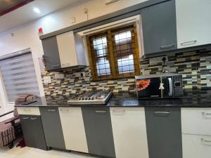 a kitchen with a microwave sitting on top of a counter at JEENA Homestay VILLA in Kollam