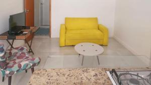 sala de estar con sofá amarillo y mesa en Apartamento Felipe de Oliveira en Río de Janeiro