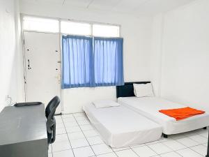 a bedroom with two beds and a desk and a window at OYO Life 92630 Siliwangi Residence 63 in Bandung