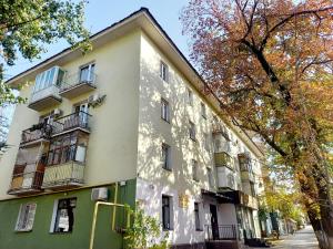 um edifício branco e verde com varandas numa rua em "В центре города" Квартира - "Downtown" Apartment em Almaty