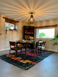 a dining room with a table and chairs on a rug at Coté jardin in Sainte-Suzanne