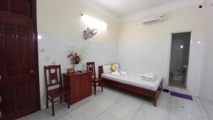 ein kleines Zimmer mit einem Bett und zwei Stühlen. in der Unterkunft THAI BINH MOTEL in Đà Nẵng