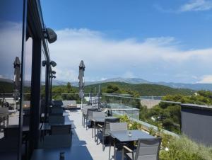 a row of tables and chairs on a balcony with mountains at Moro Inn in Korčula