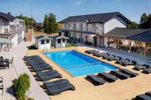 a large swimming pool with lounge chairs next to a house at SEO2 Rewal - Apartamenty z osobnym wejściem, grzany basen, darmowe sauny, parking, grill, wifi in Rewal