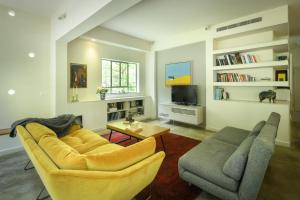 een woonkamer met 2 stoelen, een bank en een tv bij Spacious & Green 3BR Apt w Balcony in City Center by Sea N' Rent in Tel Aviv
