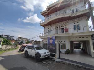 un coche blanco estacionado frente a un edificio en OYO Life 92637 Kost Arya Exclusive en Jambi