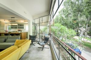salon z kanapą i krzesłami na balkonie w obiekcie Spacious & Green 3BR Apt w Balcony in City Center by Sea N' Rent w Tel Awiwie