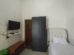 a bedroom with a bed and a cabinet and a television at OYO Life 92637 Kost Arya Exclusive in Jambi