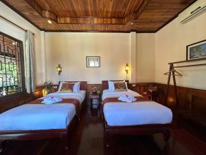 a room with three beds with white sheets at Ammata Boutique Villa in Luang Prabang