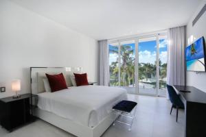 Dormitorio blanco con cama y ventana grande en LAS PALMAS 78 ACCESS TO EDEN ROC BEACH CLUB GOURMET CHEF BUTLER MAiD 2 GOLF CARTS, en Punta Cana