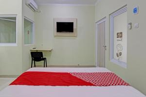 - une chambre blanche avec une couverture rouge sur un lit dans l'établissement OYO 92642 Tumesa Homestay 2 Syariah, à Semarang